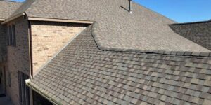 Brick house with shingled roof under blue sky.