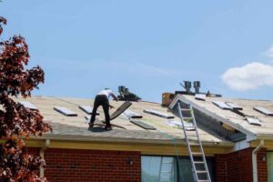 Worker repairing roof on sunny day.