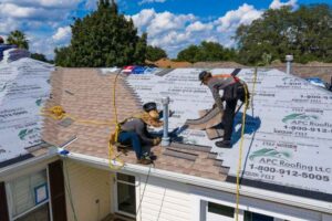 Roofers installing shingles on a house roof.